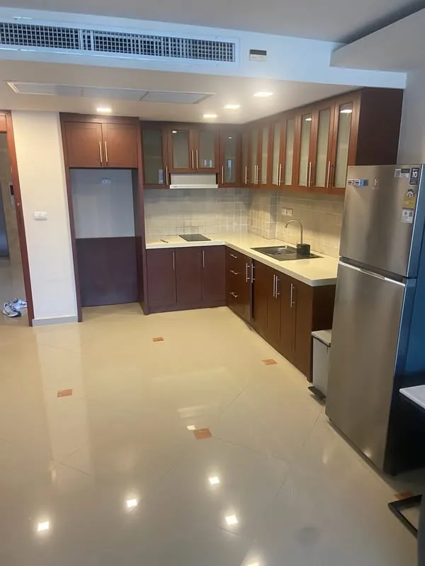 Wood-finish fitted condo kitchen with glass-fronted wall units, by Planet Kitchen in Pattaya